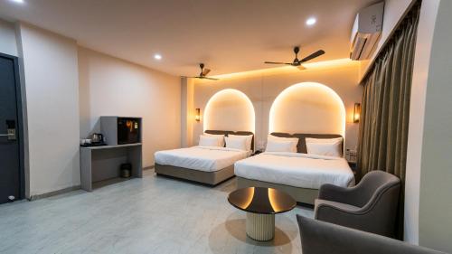 a hotel room with two beds and a tv at Hotel Pinaki Inn in Ujjain