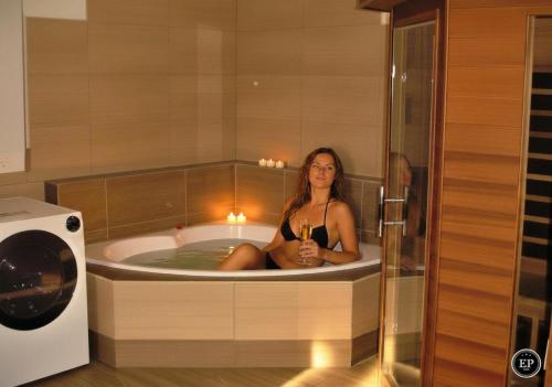 a woman sitting in a bath tub with a glass of wine at Villa Ametyst in Štúrovo