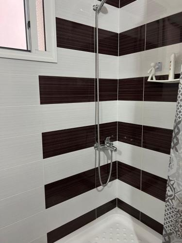 a shower with black and white stripes in a bathroom at Sunshine Apartment in Sarandë