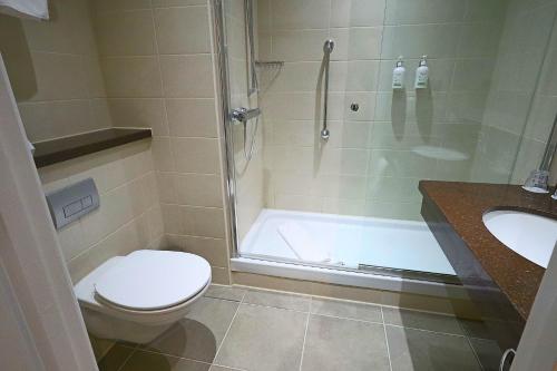 a bathroom with a shower and a toilet and a sink at Holiday Inn London Luton North in Luton