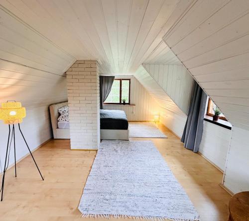 a attic bedroom with a bed and a white rug at Mäeotsa Country House in Laulasmaa