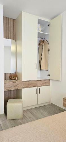 a dressing room with white cabinets and a mirror at Value Living Apartment in Ferizaj