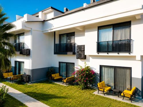 a white building with yellow chairs in the yard at Side Mira Palace & Spa in Side