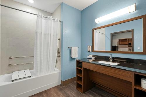 a bathroom with a tub and a sink and a mirror at HomeTowne Studios by Red Roof Bradenton in Bradenton