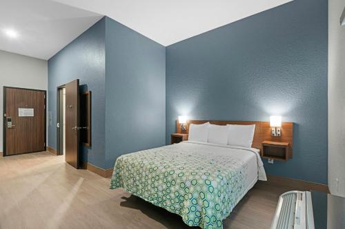 a bedroom with a bed and a blue wall at HomeTowne Studios by Red Roof Bradenton in Bradenton