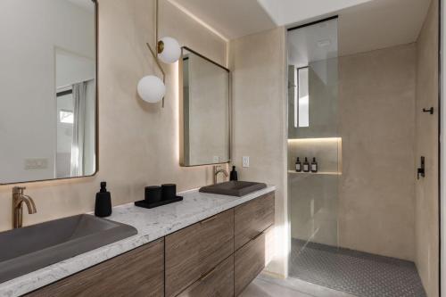 a bathroom with two sinks and a mirror and a shower at Windsong Modern compound w pool spa in Yucca Valley