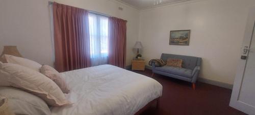 a bedroom with a bed and a chair and a window at Mary's Place in Devonport