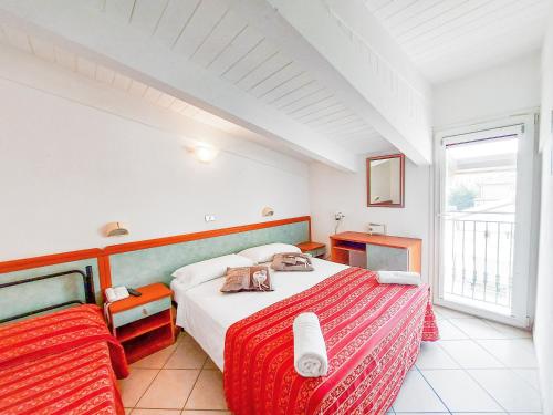 a white bedroom with a bed and a window at Hotel Explorer in Cervia