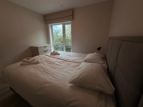 a bedroom with a white bed with a window at Geirangerbooking in Geiranger
