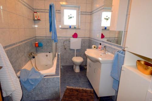 a bathroom with a sink and a toilet and a tub at Apartments Celebrini in Malinska