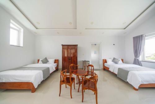 a room with three beds and a table and chairs at TRUNG LÀI HOTEll in Ấp Thái Thương