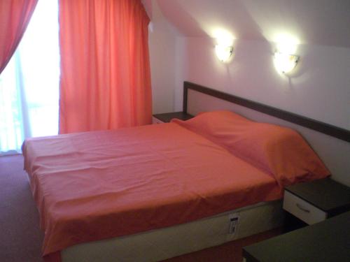 a bedroom with a bed with an orange blanket at Hotel Bellisimo in Lozenets