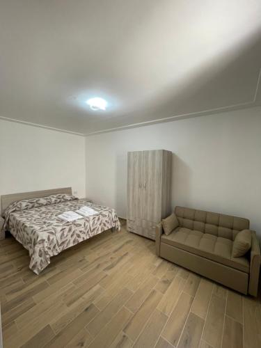 een slaapkamer met een bed en een bank erin bij Dimora AVE in Aieta