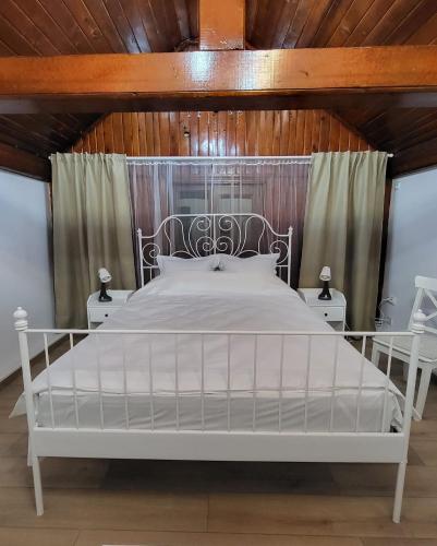 a white bed in a bedroom with a wooden ceiling at Retro House in Pantelimon