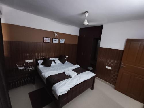 a bedroom with a bed with white sheets and pillows at Hovato Brown in Nedumbassery