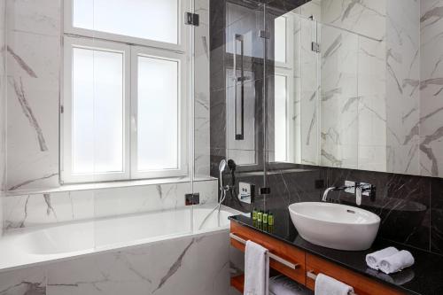 a bathroom with a sink and a tub and a window at Kosher Hotel King David Prague in Prague