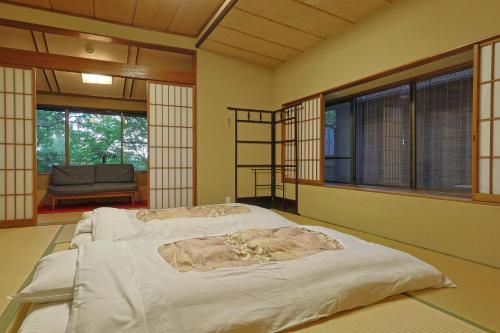 a large bed in a room with windows at Kotonoyado Musashino in Nara