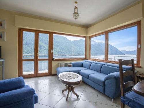 a living room with a blue couch and large windows at Apartment Miralago by Interhome in Oria