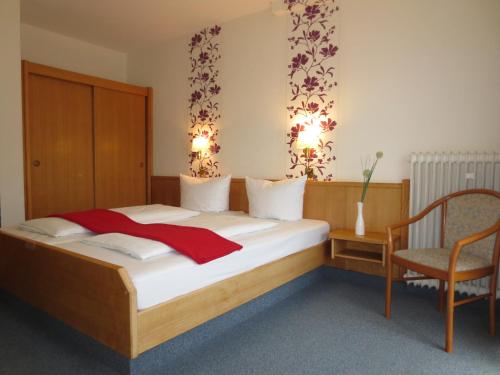 a bedroom with a large bed and a chair at Hotel Krone in Bad Münster am Stein-Ebernburg