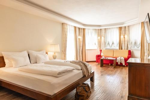 a bedroom with a large bed and a red chair at Hotel Fameli in Valdaora