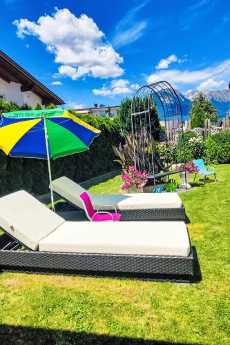 a group of chaise lounge chairs and an umbrella at Apartment Helga by Interhome in Karres