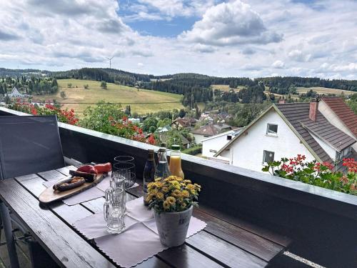 a table with a bottle of wine and flowers on a balcony at Apartment Blackforest Birdnest by Interhome in Schonach