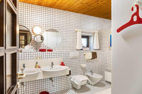 a white tiled bathroom with two sinks and a toilet at Villa Mona Lisa in Seefeld in Tirol