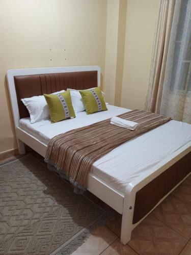 a bed with yellow pillows and a brown blanket at Voi town CBD homes in Voi