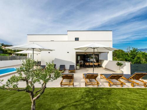 a patio with chairs and umbrellas in front of a house at Villa Antica by Interhome in Lopar