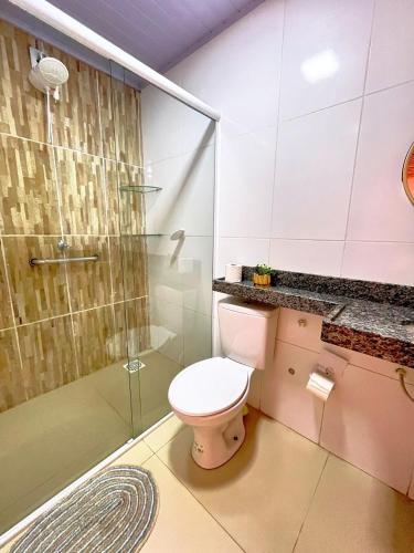 a bathroom with a toilet and a glass shower at Loft Verde - Pousada Vila Dondom in Luis Correia