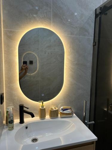 a person taking a picture of a bathroom sink with a mirror at Ademi cottage in Koshkolʼ