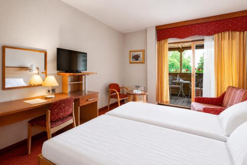 a hotel room with a bed and a desk and a room at Terme Banovci - Hotel Zeleni Gaj in Banovci
