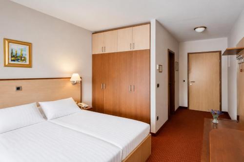 a bedroom with a large white bed and wooden cabinets at Terme Banovci - Hotel Zeleni Gaj in Banovci