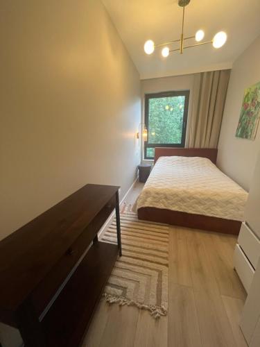 a bedroom with a bed and a desk and a window at Apartament indyjski Legnica in Legnica