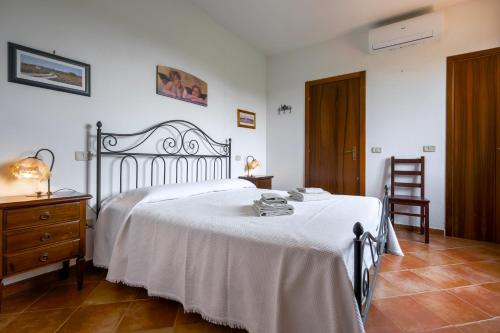 a bedroom with a white bed and a wooden dresser at Bed and Breakfast Torrette Etrusche in Capalbio
