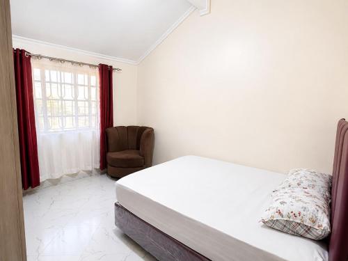 a white bedroom with a bed and a chair at Nest at Imaara in Nairobi