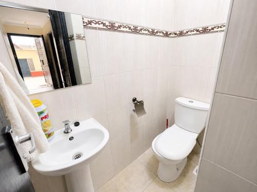 a white bathroom with a toilet and a sink at Nest at Imaara in Nairobi