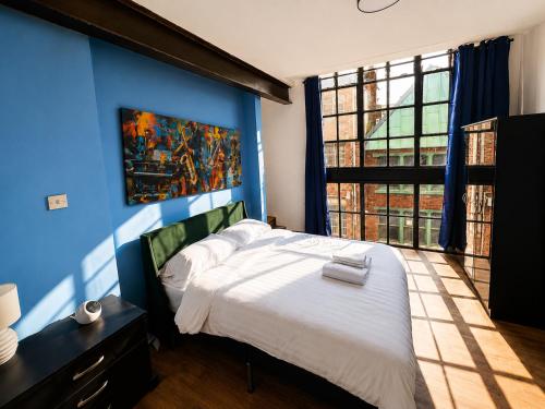 a bedroom with a blue wall with a bed and a window at 2BR Central Apt - Parking -2 Baths - Bars & Trains in Liverpool
