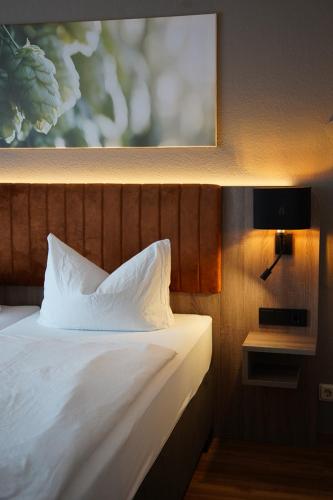 a bed with white pillows and a picture on the wall at Schinkels Brauhotel in Witzenhausen
