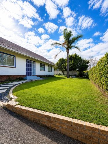 a house with a large yard with a palm tree at Three on Firmount in Somerset West