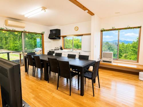 a dining room with a black table and chairs at サウナパラダイス富山 in Minamiboso