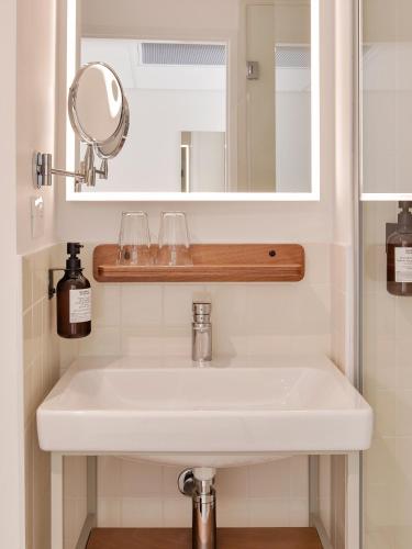 a white sink in a bathroom with a mirror at Alfred Hotels Toulouse Victor Hugo - Hôtel Rénové in Toulouse