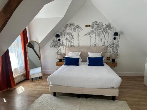 a bedroom with a large white bed with blue pillows at Hôtel Château Héloïse in Mérélessart