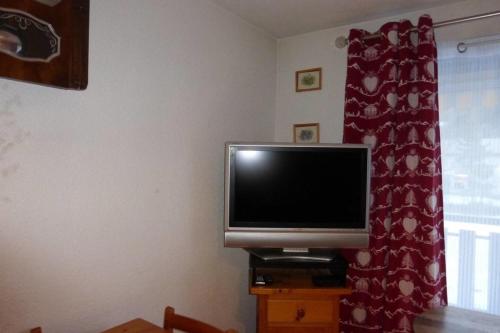 a flat screen tv sitting on a stand next to a window at Studio with mountain view in Barcelonnette in Barcelonnette