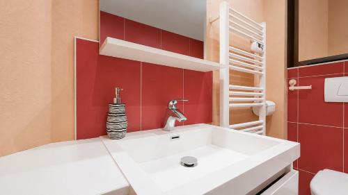 a bathroom with a white sink and red walls at T2 Cosy - Proche Dijon -Terrasse - Parking in Pichanges
