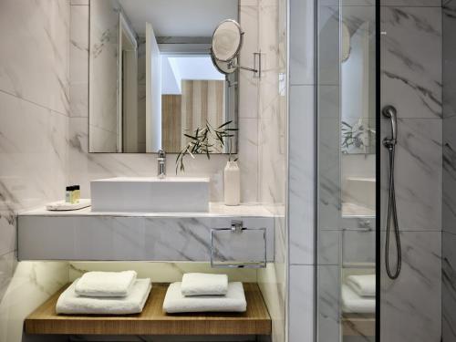 a bathroom with a sink and a mirror at Atlantica Nissaki Beach - Adults Only in Gimari