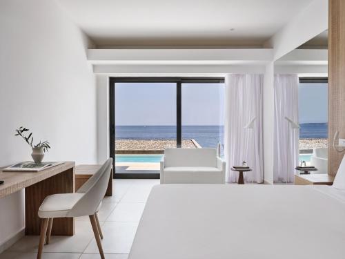 a white bedroom with a view of the ocean at Atlantica Nissaki Beach - Adults Only in Gimari