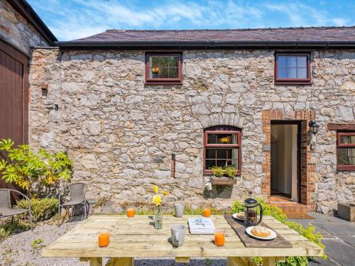 a wooden table in front of a stone house at Bluebell Cottage - Ukc6676 in Bettws-yn-Rhôs