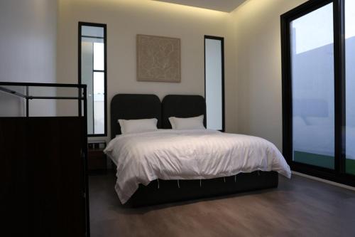 a bedroom with a bed and two large windows at Eight House villa in Jeddah