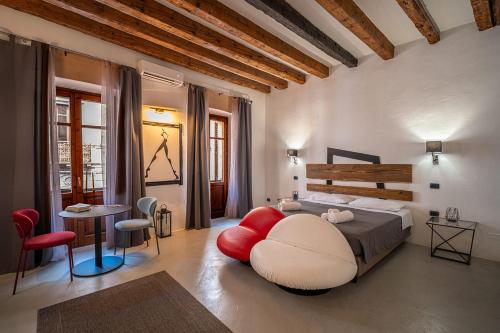 a bedroom with a large bed and a red chair at C&O Savoia Deluxe Rooms in Cagliari